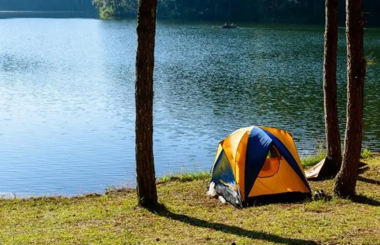 A tent sits along the shore of a lake